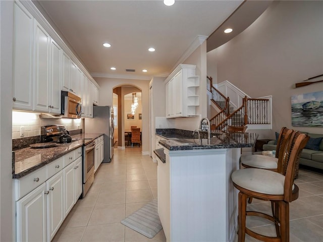4570 Bridgepointe Way Unit 148, Vero Beach, FL 32967 - kitchen with appliances with stainless steel finishes, arched walkways, a breakfast bar, open shelves, and white cabinets