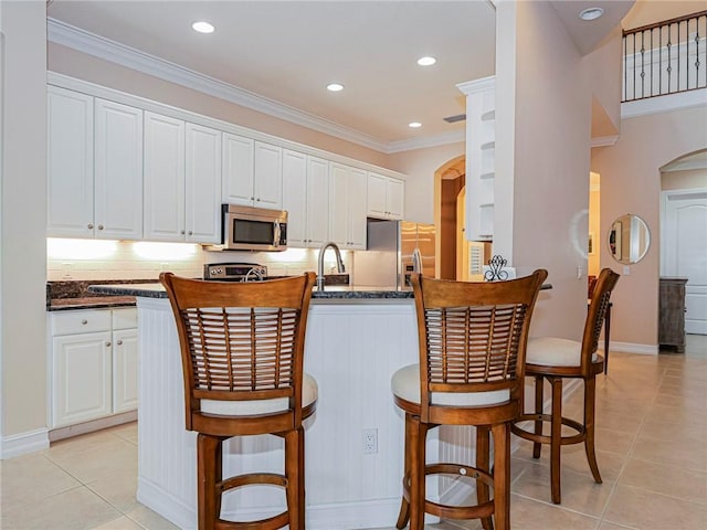 4570 Bridgepointe Way Unit 148, Vero Beach, FL 32967 - kitchen with appliances with stainless steel finishes, arched walkways, light tile patterned flooring, white cabinetry, and ornamental molding