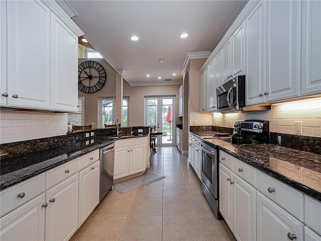 4570 Bridgepointe Way Unit 148, Vero Beach, FL 32967 - kitchen with appliances with stainless steel finishes, white cabinetry, ornamental molding, decorative backsplash, and light tile patterned flooring