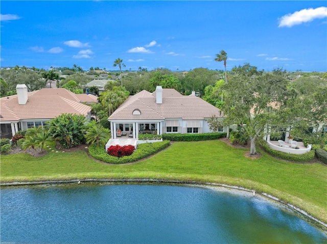 rear view of property featuring a water view and a lawn