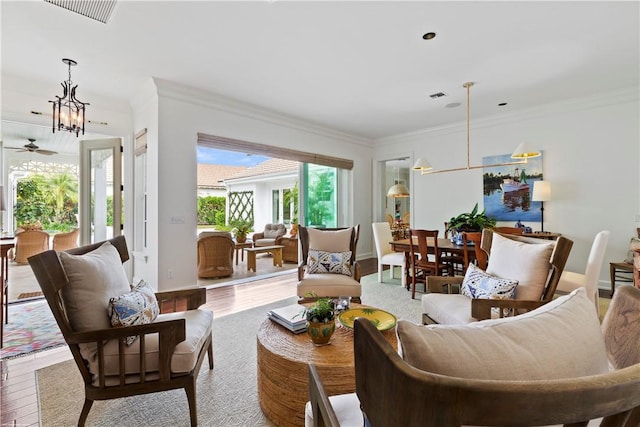 living room featuring hardwood / wood-style floors, crown molding, and a chandelier