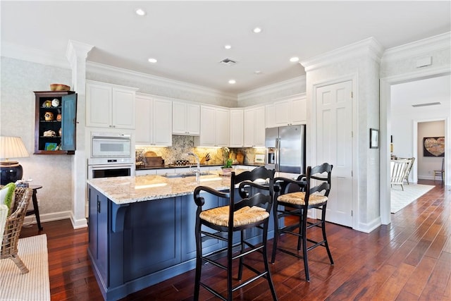 kitchen with stainless steel fridge, white cabinetry, a kitchen island with sink, and oven