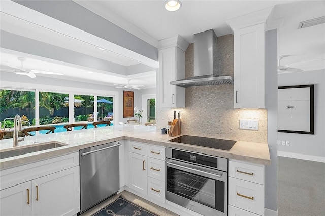 976 25th St, Vero Beach, FL 32960 - kitchen with wall chimney exhaust hood, stainless steel appliances, ceiling fan, tasteful backsplash, and white cabinetry