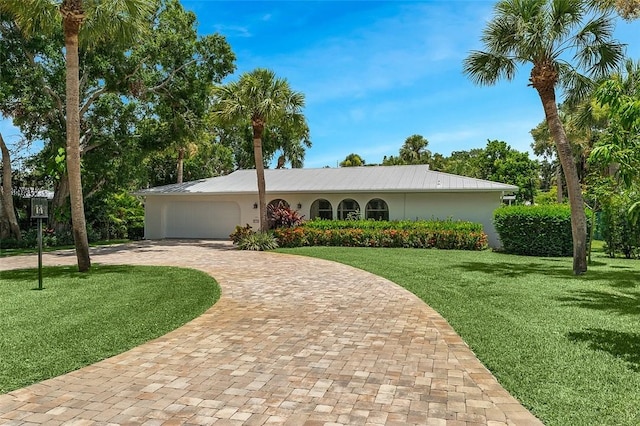 976 25th St, Vero Beach, FL 32960 - single story home featuring curved driveway, a front lawn, an attached garage, a metal roof, and stucco siding