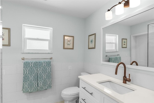 976 25th St, Vero Beach, FL 32960 - bathroom featuring tile walls, healthy amount of natural light, vanity, and a wainscoted wall