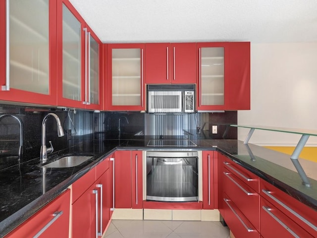 kitchen featuring stainless steel microwave, a sink, wall oven, and red cabinetry