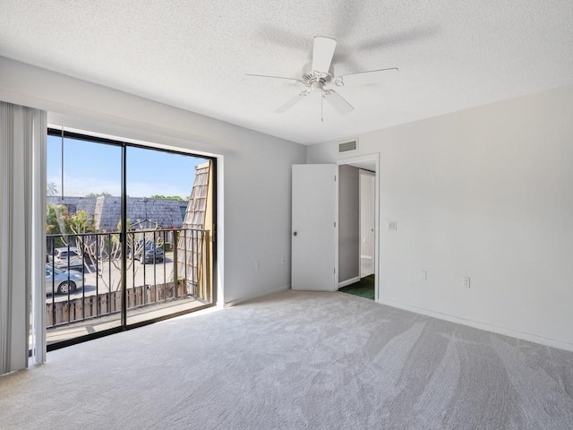 empty room with a textured ceiling, carpet flooring, ceiling fan, and visible vents