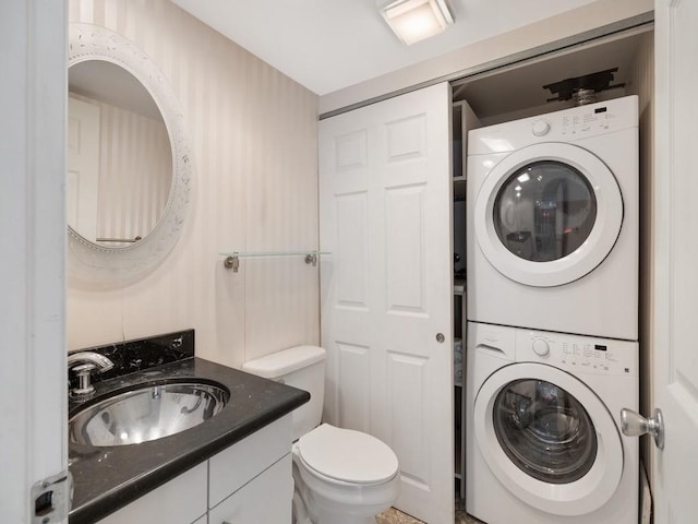 bathroom with toilet, vanity, and stacked washer / drying machine