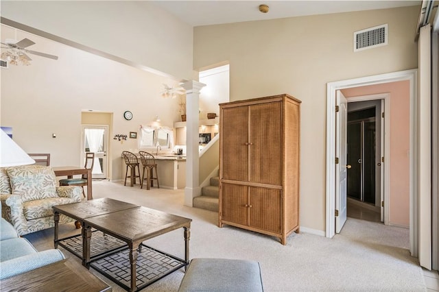 living room featuring high vaulted ceiling, light colored carpet, decorative columns, and ceiling fan