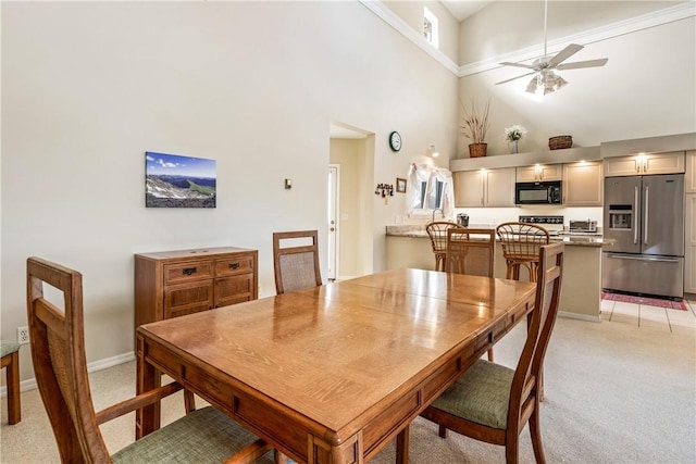 dining space featuring light carpet, ceiling fan, and a high ceiling