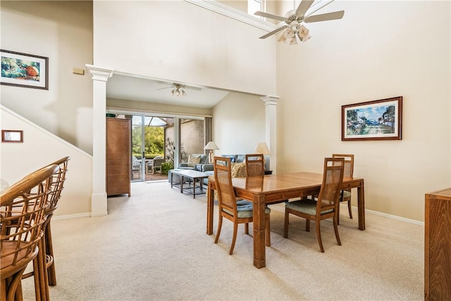 carpeted dining area featuring decorative columns, ceiling fan, and a high ceiling