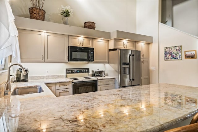 kitchen featuring light stone countertops, sink, stainless steel fridge, and electric stove