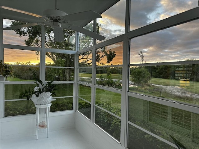 unfurnished sunroom featuring ceiling fan and plenty of natural light