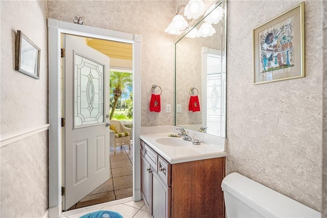 half bath featuring an inviting chandelier, vanity, toilet, and tile patterned floors