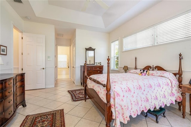 bedroom featuring a ceiling fan, a tray ceiling, visible vents, and light tile patterned floors