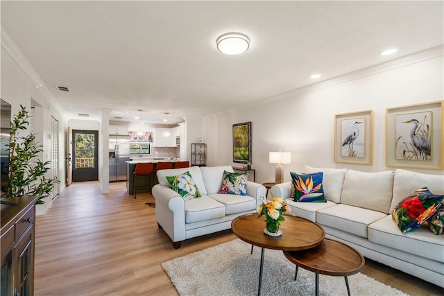 living room featuring light wood-type flooring, visible vents, recessed lighting, and crown molding