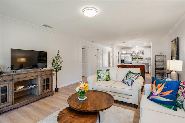 living room with visible vents, light wood-style flooring, baseboards, and ornamental molding