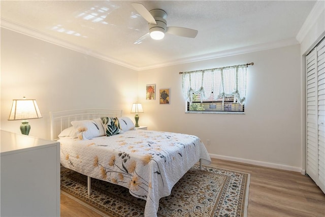 bedroom featuring baseboards, ceiling fan, ornamental molding, a closet, and light wood-type flooring