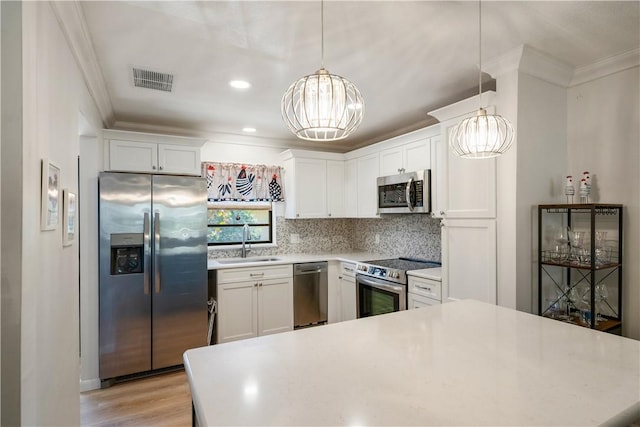 kitchen featuring crown molding, light countertops, appliances with stainless steel finishes, and a sink