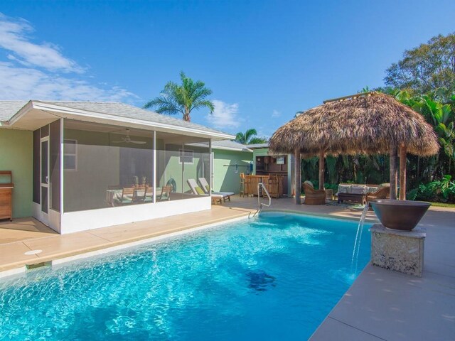 view of swimming pool featuring outdoor lounge area, a sunroom, pool water feature, exterior bar, and a patio