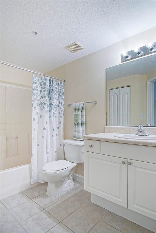 5060 Fairways Cir Unit F312, Vero Beach, FL 32967 - full bathroom with toilet, vanity, tile patterned floors, shower / tub combo, and a textured ceiling