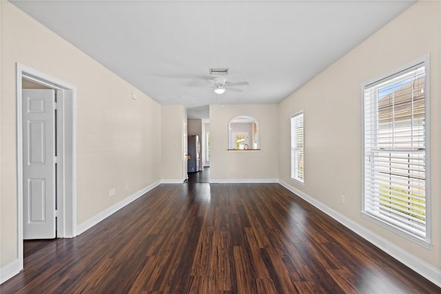 spare room featuring a ceiling fan, baseboards, and dark wood-style flooring