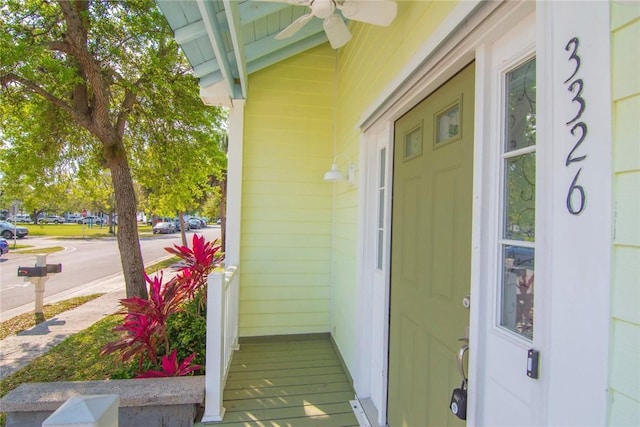 view of exterior entry featuring a porch and a ceiling fan