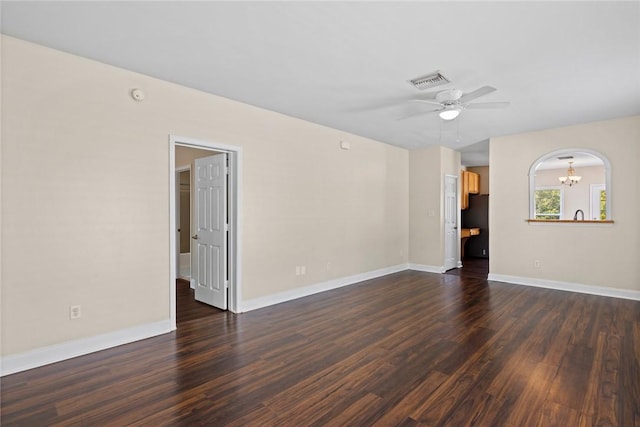 spare room with visible vents, baseboards, arched walkways, dark wood-style flooring, and ceiling fan with notable chandelier