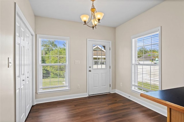 doorway to outside with baseboards, a healthy amount of sunlight, a chandelier, and dark wood-style flooring