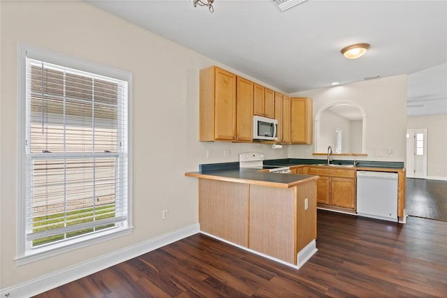 kitchen with a sink, dark wood finished floors, white appliances, a peninsula, and baseboards