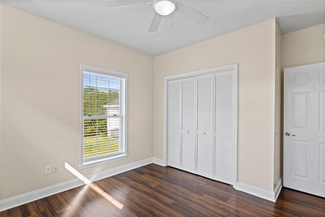 unfurnished bedroom with a closet, baseboards, dark wood finished floors, and a ceiling fan