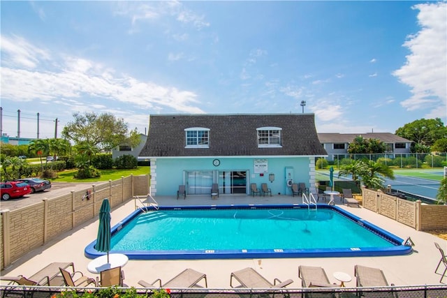 community pool with a patio area and fence