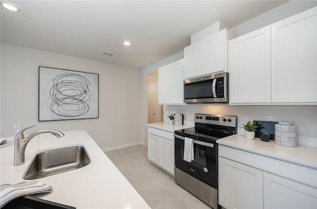 kitchen featuring recessed lighting, stainless steel appliances, white cabinets, and light countertops