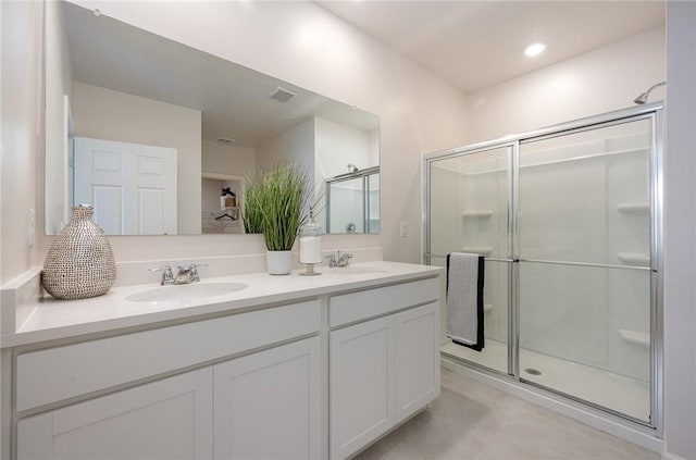 bathroom featuring double vanity, visible vents, a stall shower, and a sink