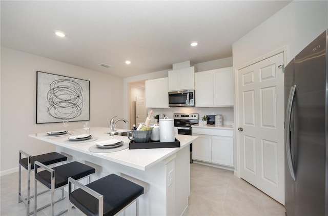 kitchen with visible vents, a breakfast bar area, light countertops, appliances with stainless steel finishes, and white cabinetry