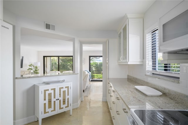 kitchen featuring light stone counters, stove, and white cabinets