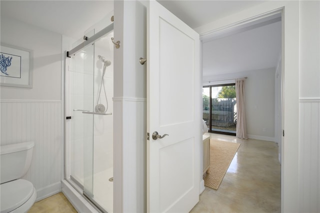 bathroom featuring toilet, concrete floors, and a shower with shower door