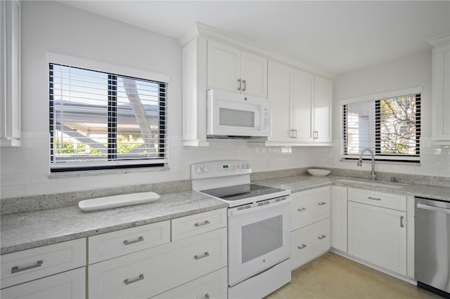 kitchen featuring sink, backsplash, white cabinets, and white appliances