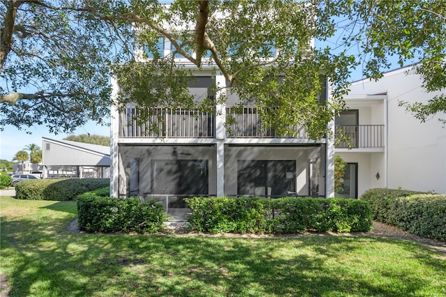 back of property with a balcony and a lawn