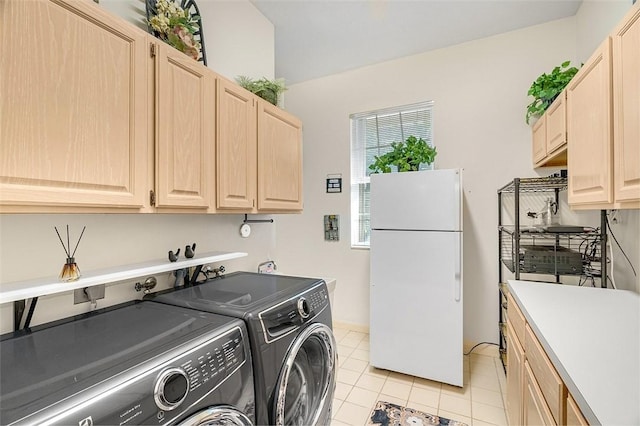 laundry area with cabinets, light tile patterned floors, and washing machine and clothes dryer