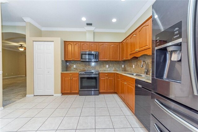 7941 Cabot Tower Pl, Vero Beach, FL 32966 - kitchen featuring appliances with stainless steel finishes, a sink, light tile patterned floors, ornamental molding, and brown cabinetry