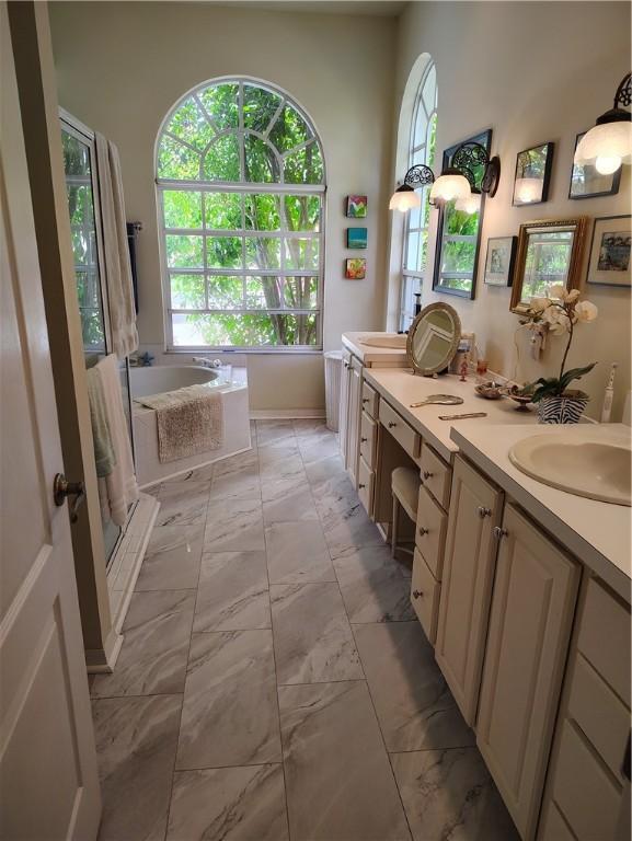 3932 58th Cir, Vero Beach, FL 32966 - bathroom with a bath, marble look tiles, and double vanity