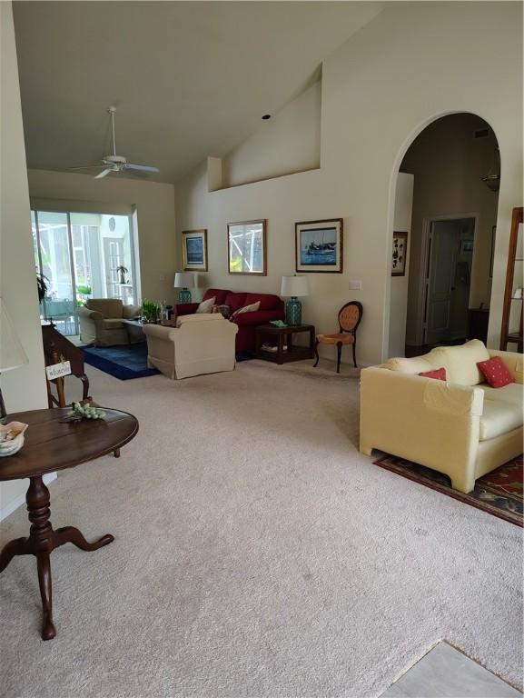 3932 58th Cir, Vero Beach, FL 32966 - carpeted living room with arched walkways, ceiling fan, and high vaulted ceiling