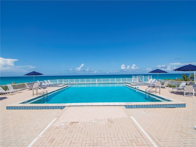 view of swimming pool featuring a water view and a patio area