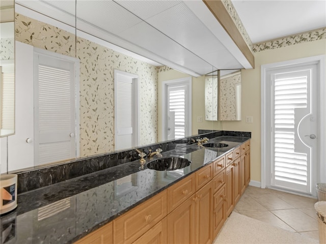 kitchen featuring sink, dark stone countertops, and light tile patterned floors