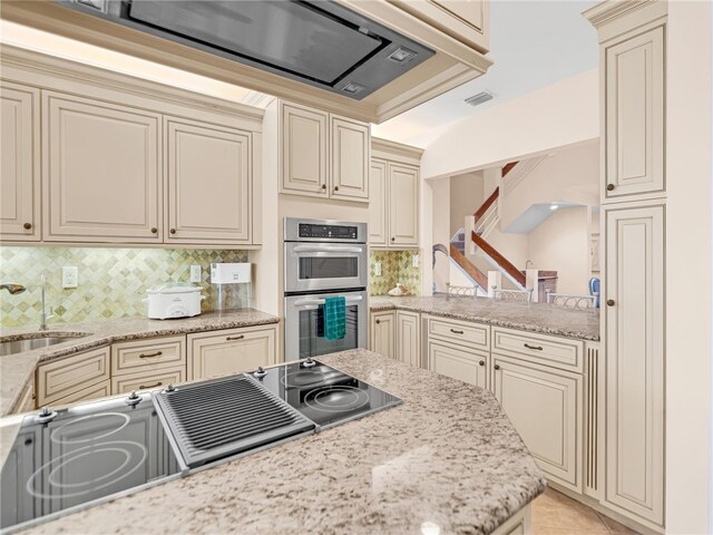 8444 Oceanside Dr Unit D31, Indian River Shores, FL 32963 - kitchen with cream cabinets, stainless steel double oven, stovetop with downdraft, and tasteful backsplash