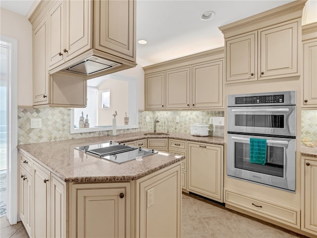 kitchen featuring appliances with stainless steel finishes, cream cabinets, sink, and light stone countertops