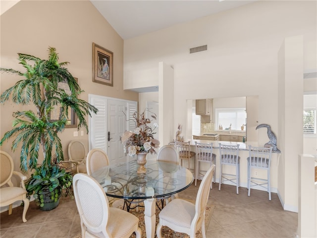 dining room featuring high vaulted ceiling and light tile patterned flooring