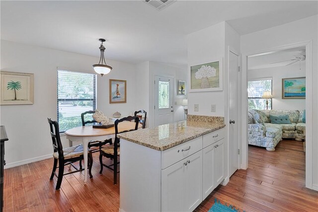 kitchen featuring white cabinetry, plenty of natural light, hardwood / wood-style floors, and decorative light fixtures