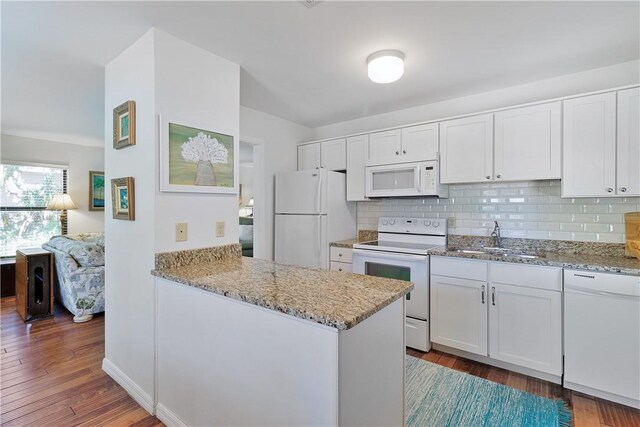 kitchen with white appliances, dark wood-type flooring, white cabinets, sink, and tasteful backsplash